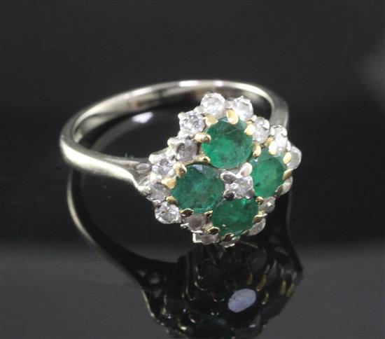 An 18ct white and yellow gold, emerald and diamond cluster ring, claw set with four emeralds and seventeen old cut diamonds,